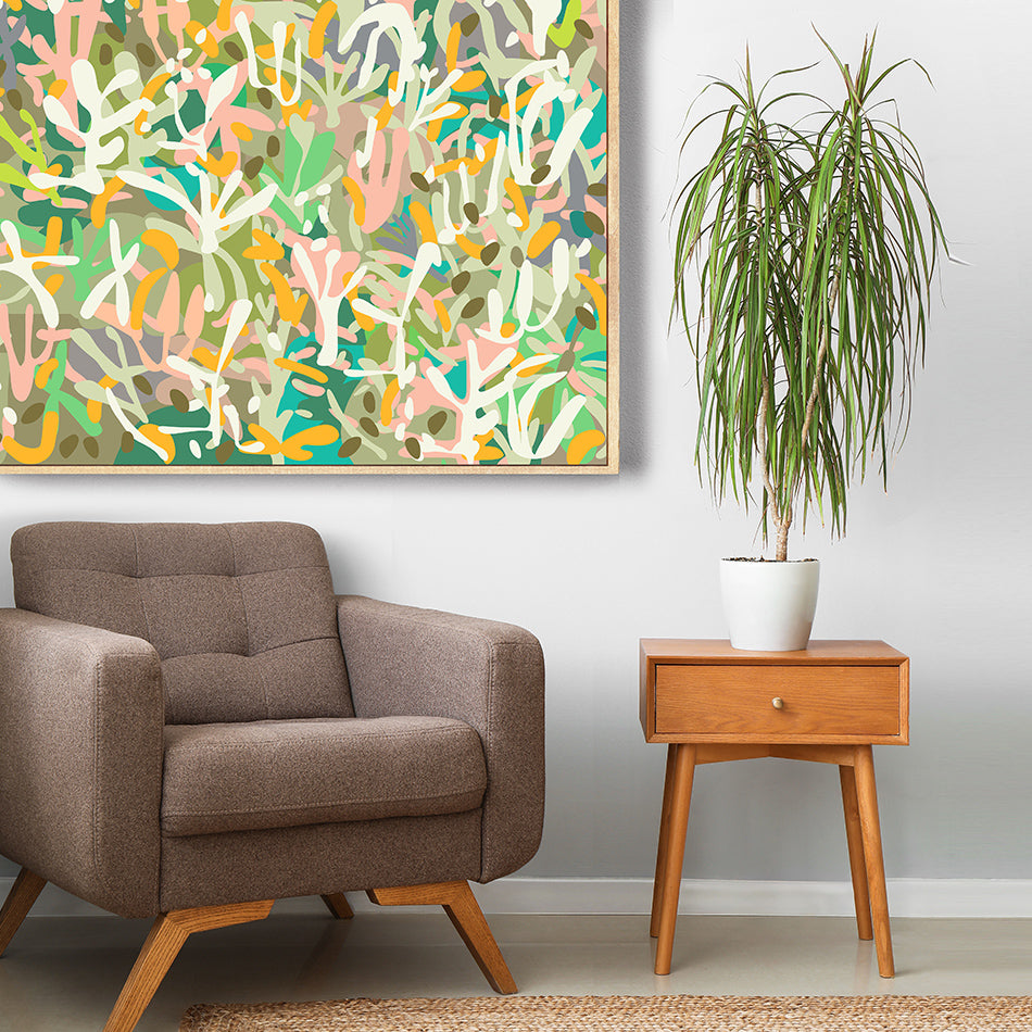 Brown armchair and wooden side table with a plant in a room featuring abstract art.