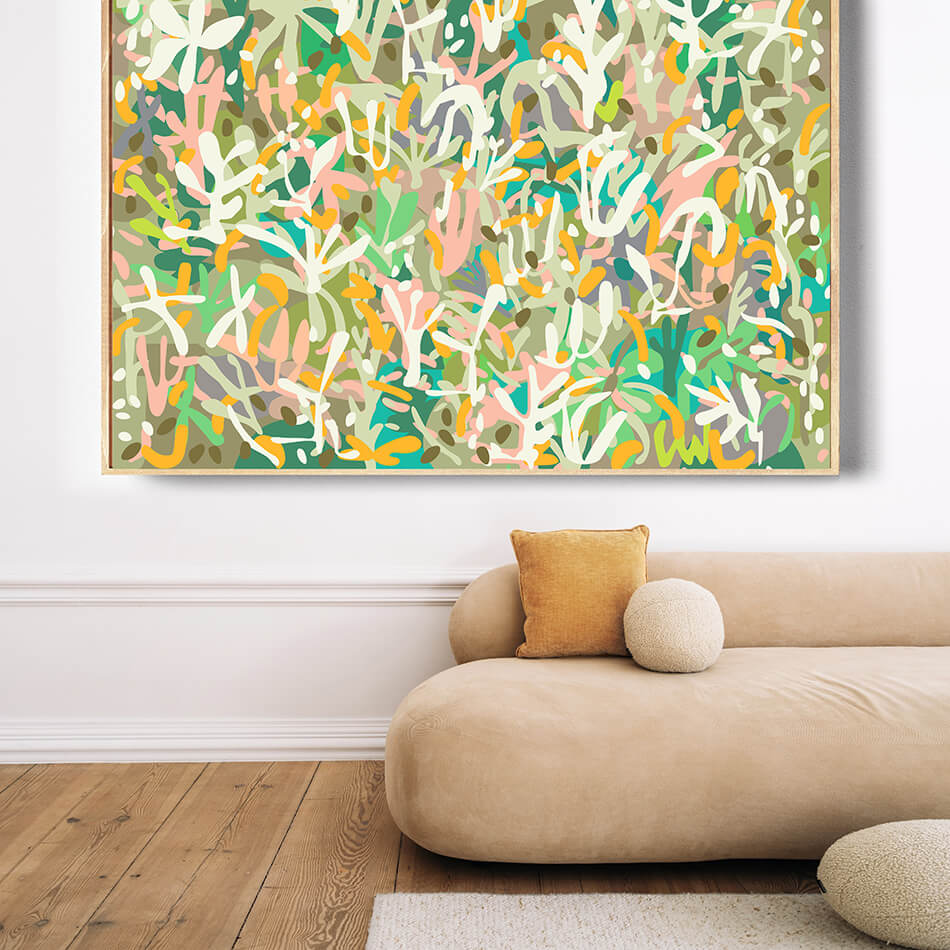 Abstract colorful painting on a wall above a beige sofa with a wooden floor.